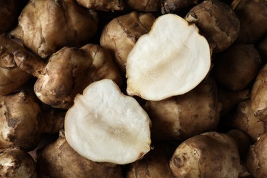 Photo of Whole and cut Jerusalem artichokes as background, top view