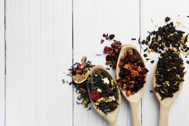 Photo of Spoons with dried herbal tea leaves and fruits on white wooden table, flat lay. Space for text