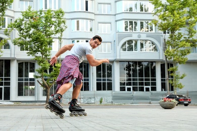 Photo of Handsome young man roller skating outdoors. Recreational activity