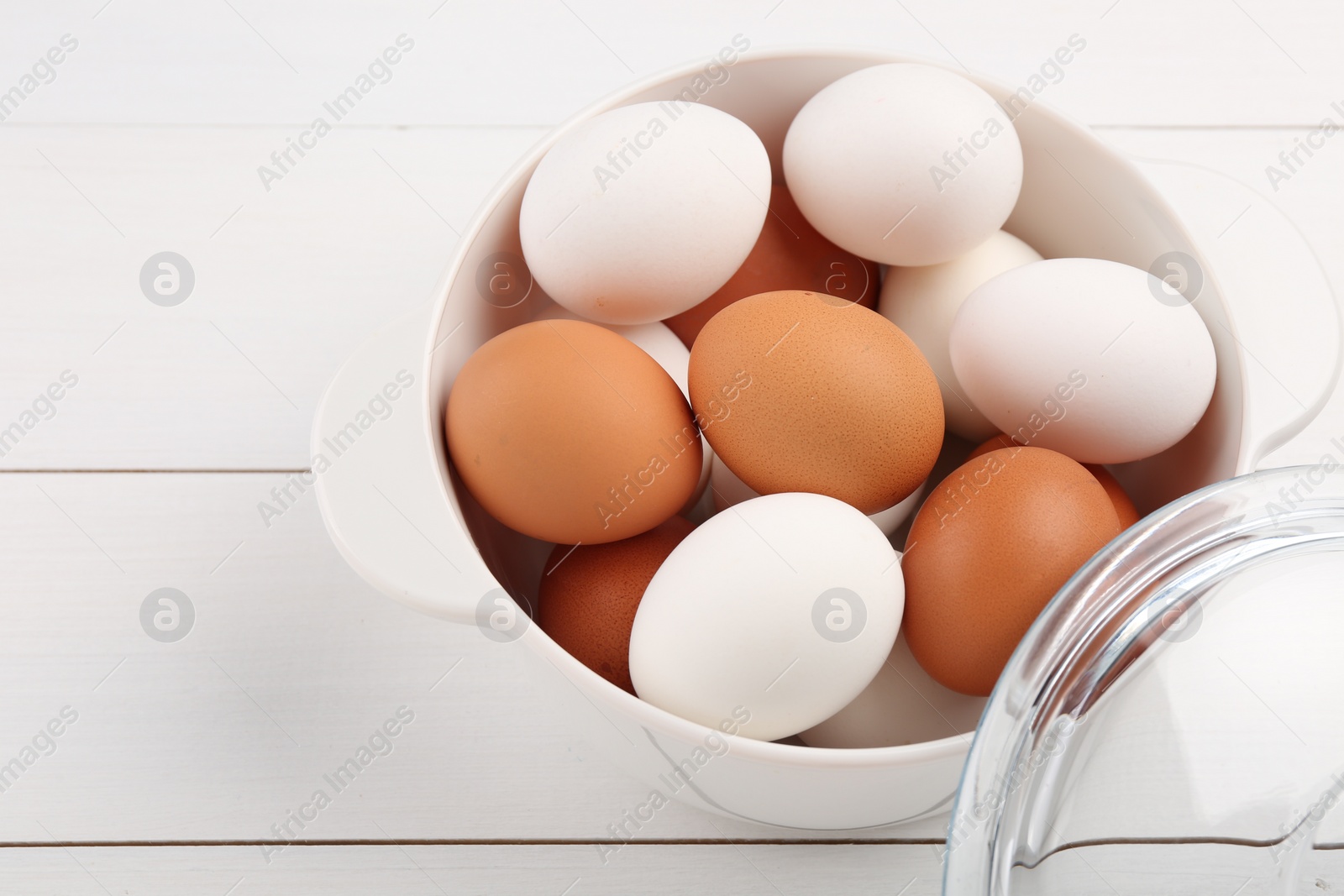 Photo of Unpeeled boiled eggs in saucepan on white wooden table, closeup