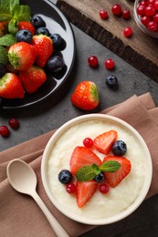 Delicious semolina pudding with berries and mint served on grey table, flat lay