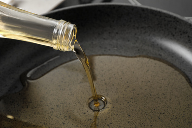 Pouring cooking oil from bottle into frying pan, closeup