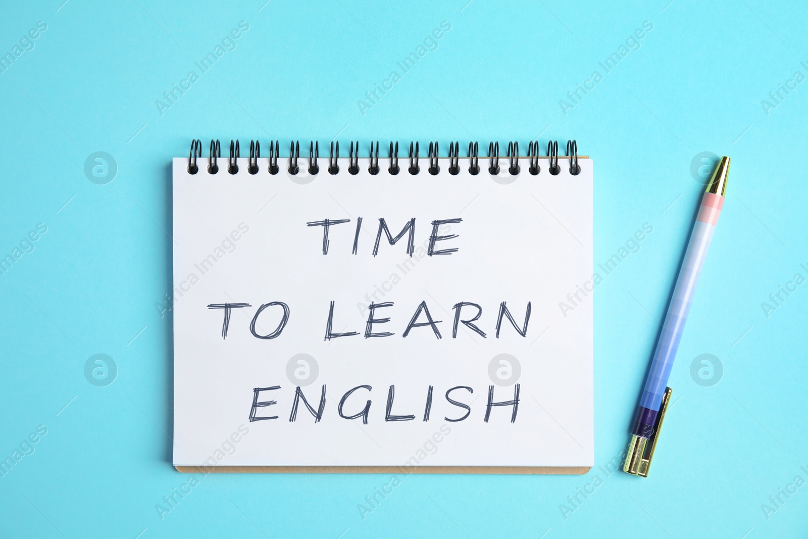 Image of Notebook with text Time To Learn English and pen on light blue background, top view