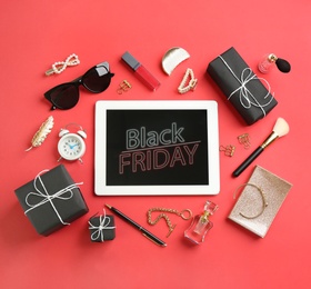 Photo of Flat lay composition with tablet, gifts and accessories on red background. Black Friday sale