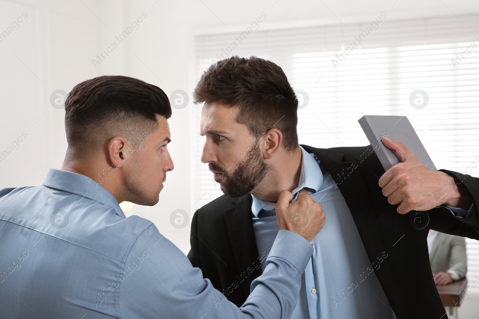 Photo of Emotional colleagues fighting in office. Workplace conflict