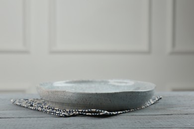Photo of Beautiful ceramic plate and napkin on gray wooden table indoors, space for text