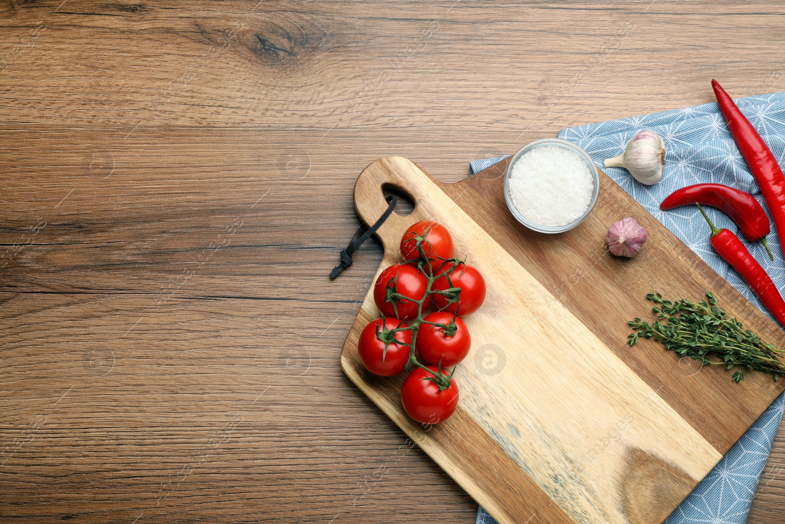 Photo of Cutting board and vegetables on wooden table, flat lay with space for text. Cooking utensil