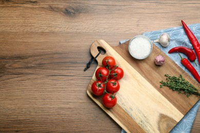 Photo of Cutting board and vegetables on wooden table, flat lay with space for text. Cooking utensil
