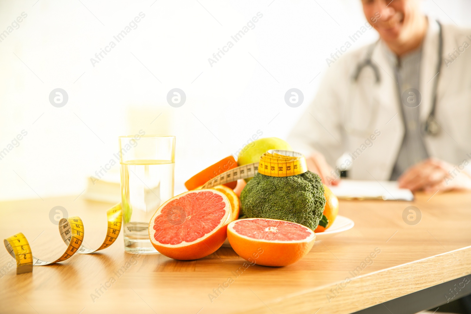 Image of Healthy products, measuring tape and blurred nutritionist on background