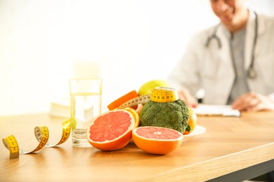 Image of Healthy products, measuring tape and blurred nutritionist on background