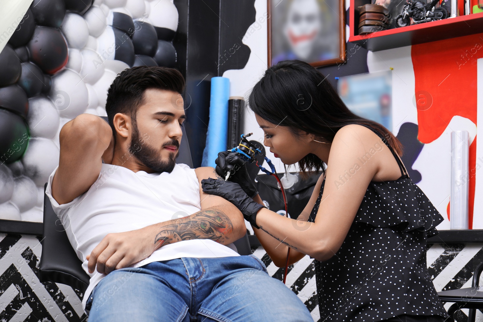 Photo of Professional artist making tattoo with machine in salon