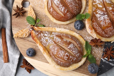 Delicious pears baked in puff pastry with powdered sugar served on table, top view