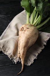 Photo of Fresh sugar beet with leaves on black wooden table