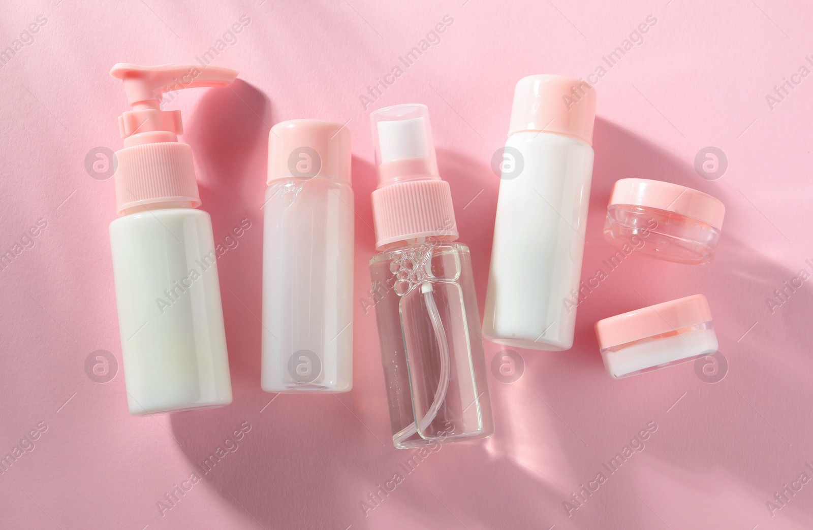 Photo of Cosmetic travel kit on pink background, top view