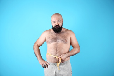 Photo of Fat man with measuring tape on color background. Weight loss