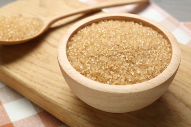 Photo of Brown sugar in bowl and spoon on table, closeup