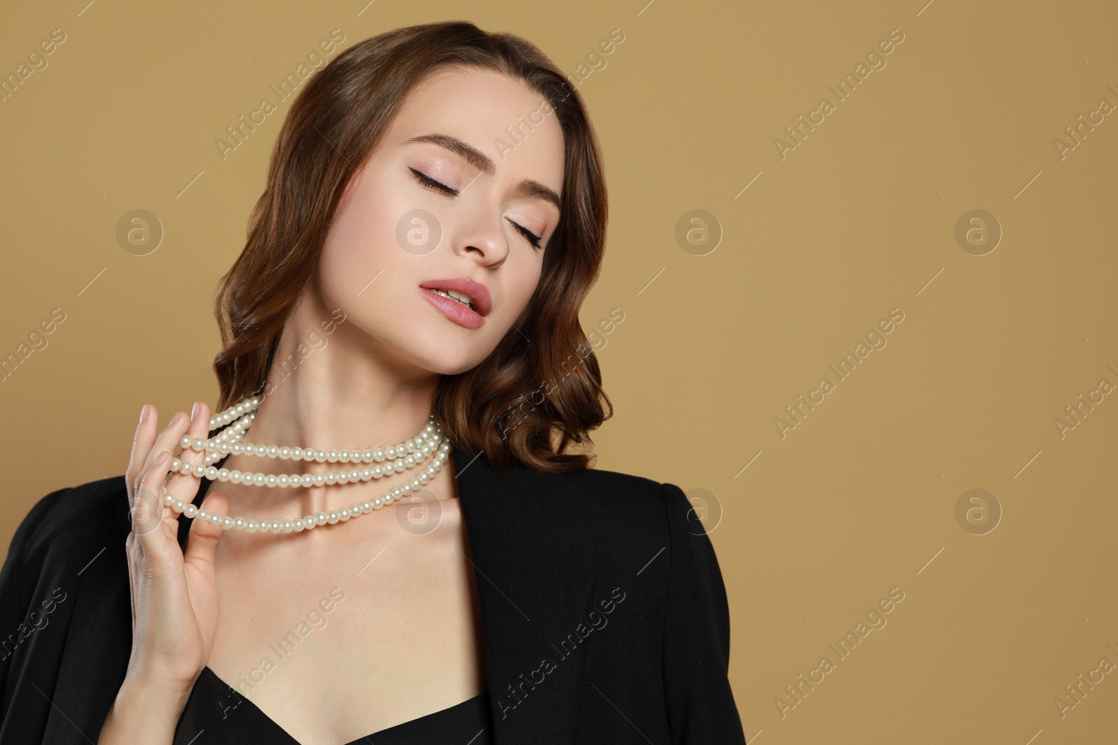 Photo of Young woman with elegant pearl necklace on brown background, space for text