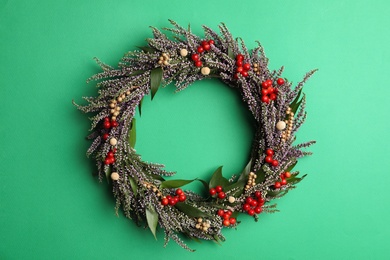 Photo of Beautiful heather wreath with berries on green background, top view. Autumnal flowers