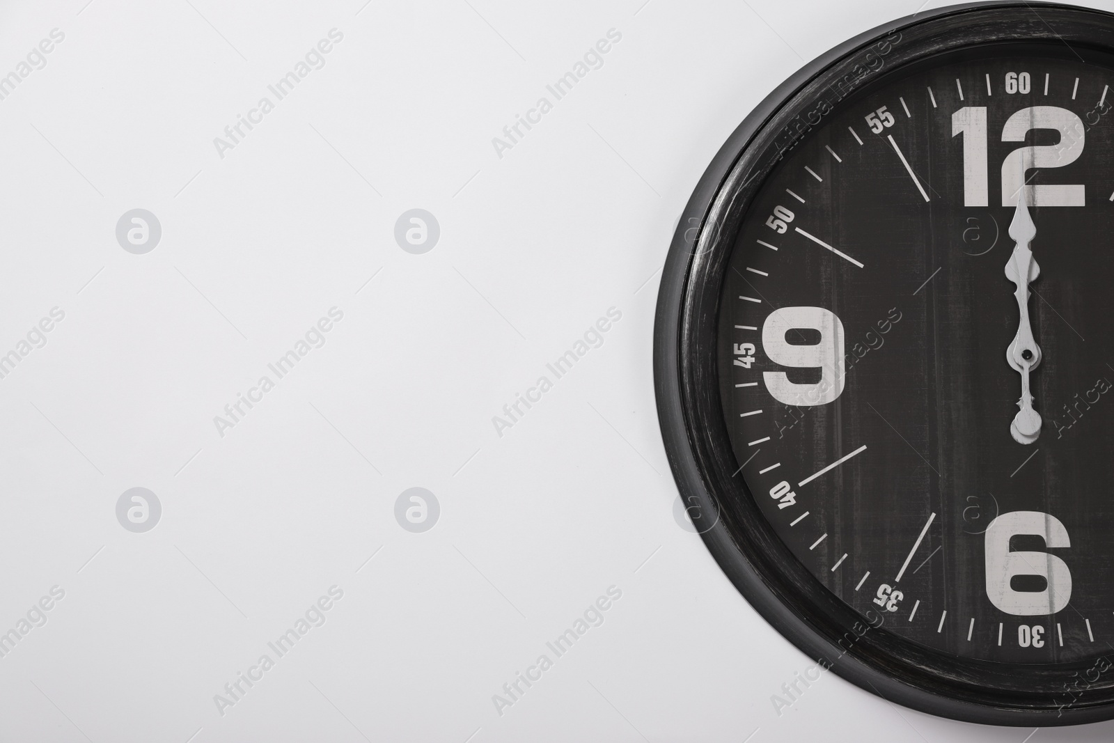 Photo of Stylish analog clock hanging on white wall, space for text