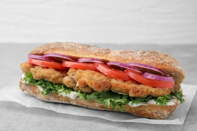 Delicious sandwich with schnitzel on grey table, closeup