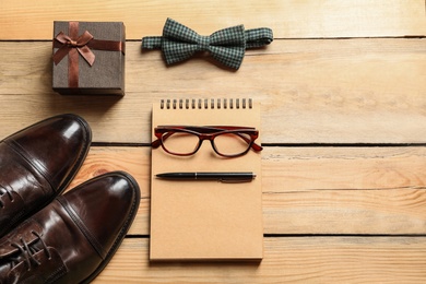 Photo of Flat lay composition with shoes, notebook, tie and gift box on wooden background. Father's day celebration