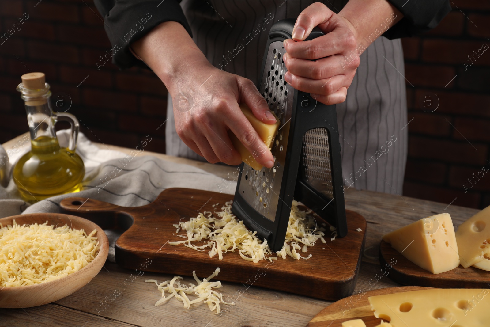 Photo of Woman grating cheese at wooden table, closeup