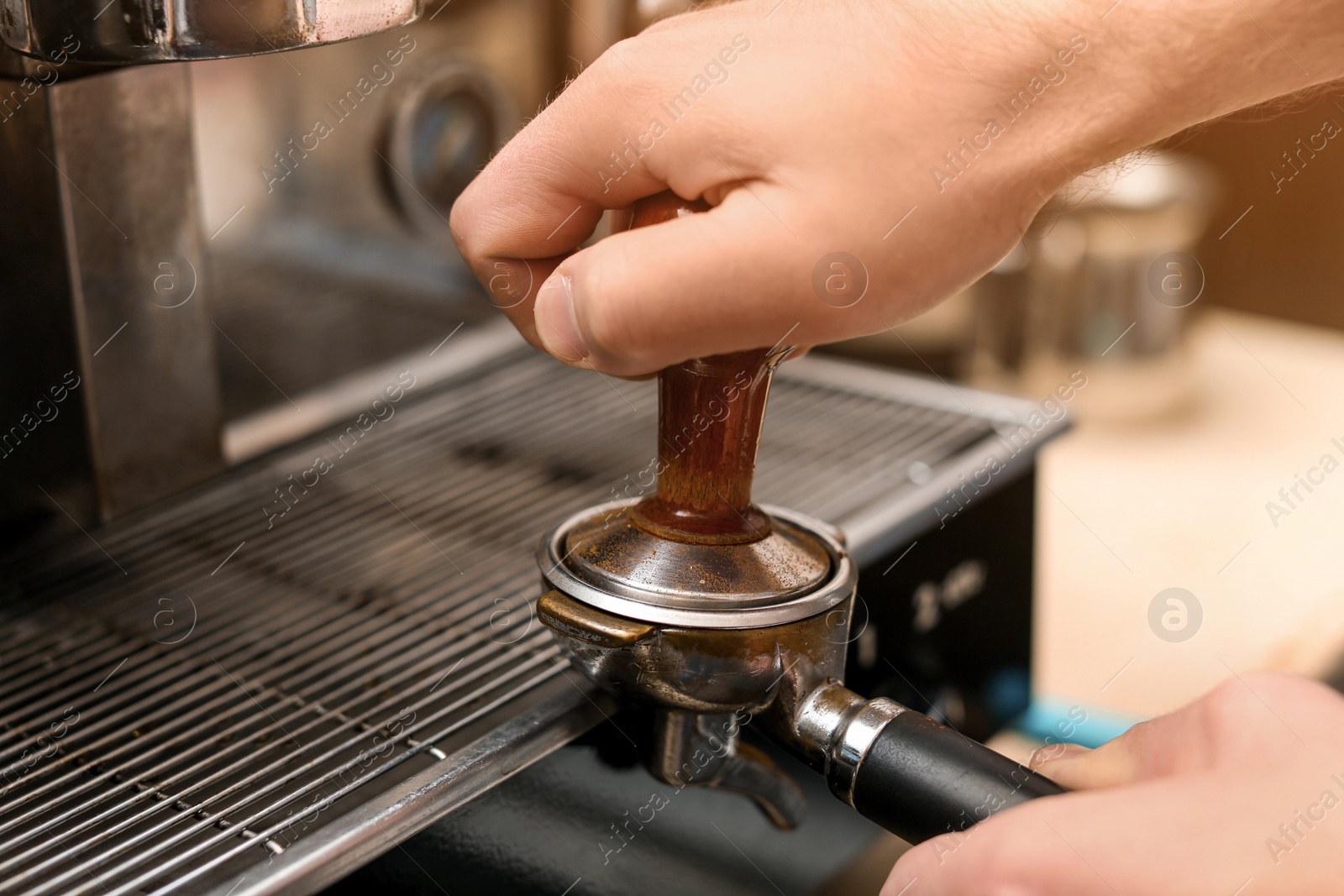 Photo of Male barista making espresso using professional coffee machine, closeup