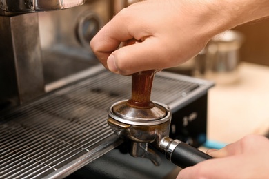 Photo of Male barista making espresso using professional coffee machine, closeup