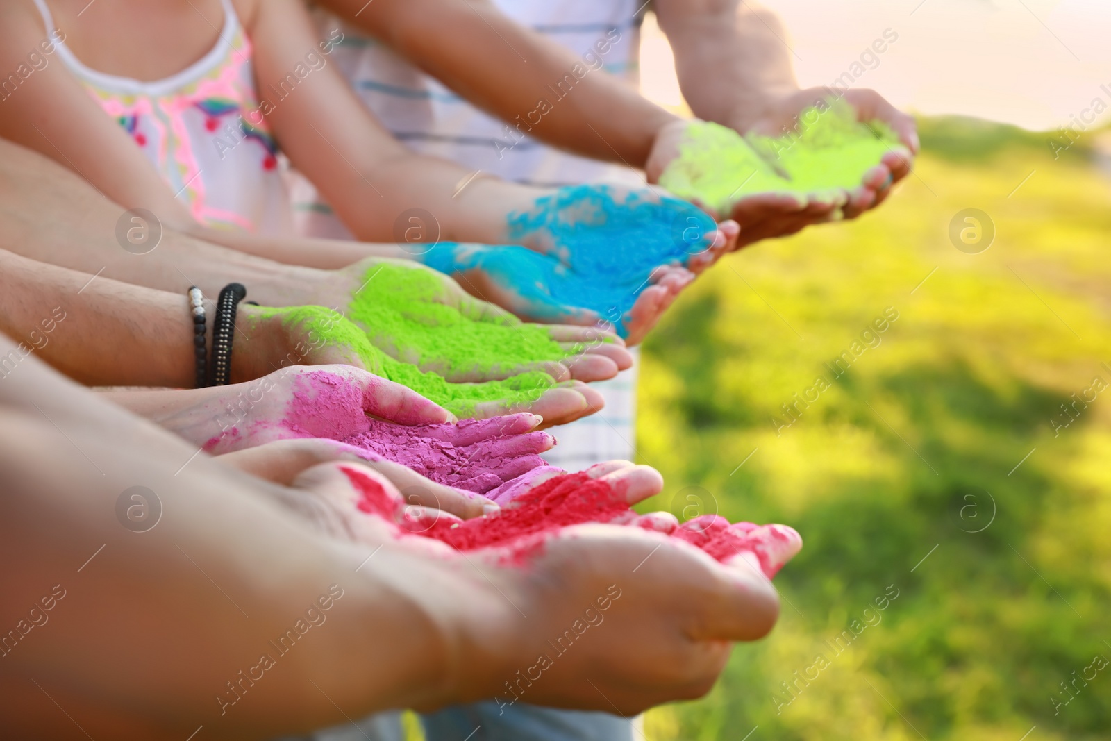 Photo of Friends with colorful powder dyes outdoors, closeup. Holi festival celebration