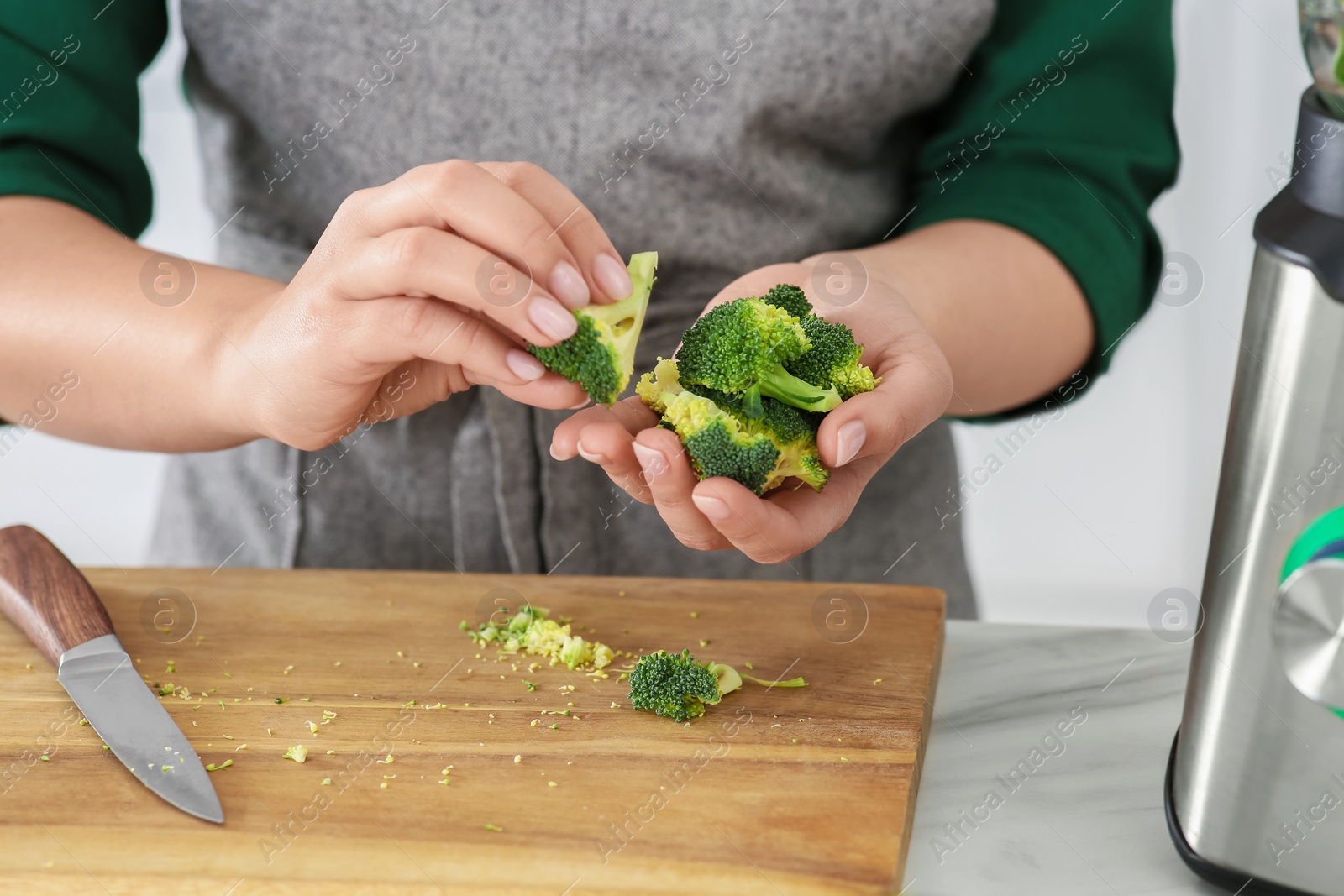 Photo of Woman with broccoli for smoothie at table, closeup