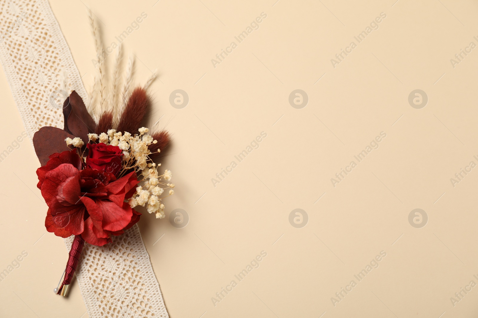 Photo of Stylish red boutonniere and ribbon on beige background, top view. Space for text