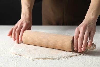 Photo of Woman rolling raw dough at table, closeup