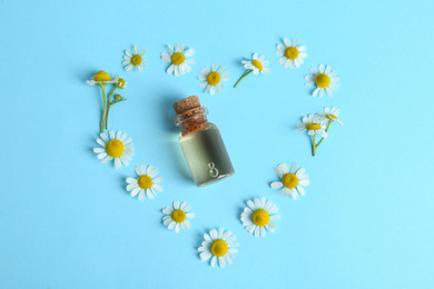 Flat lay composition with chamomile essential oil on light blue background