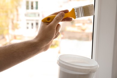 Photo of Man painting window frame at home, closeup