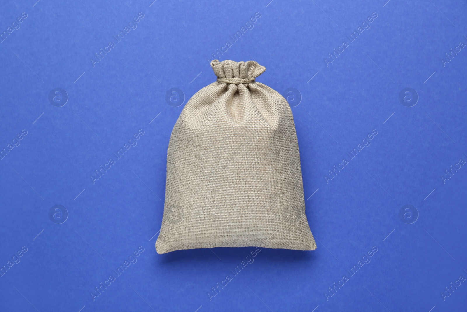 Photo of Tied burlap bag on blue background, top view