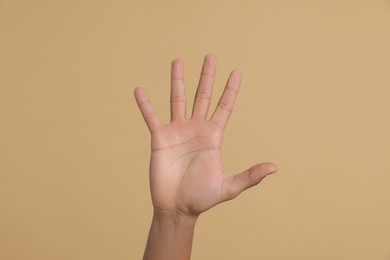 Man giving high five on beige background, closeup of hand