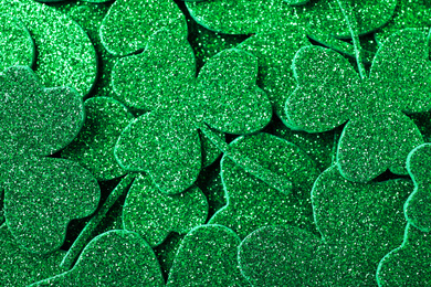 Photo of Glitter green clover leaves as background, top view. St. Patrick's Day celebration