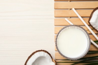 Photo of Glass of delicious vegan milk and coconuts on white wooden table, flat lay. Space for text