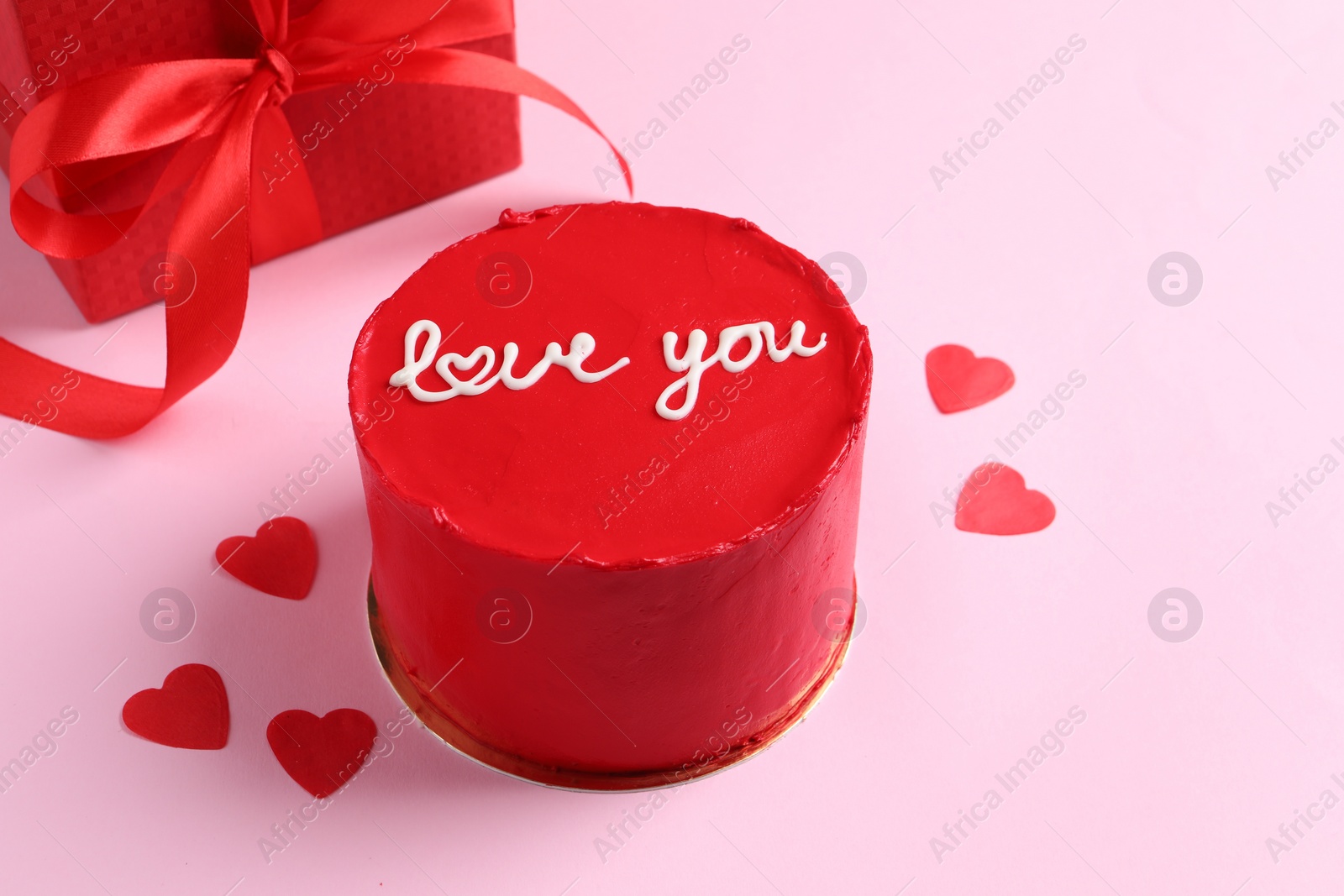 Photo of Bento cake with text Love You, gift box and paper hearts on pink table. St. Valentine's day surprise