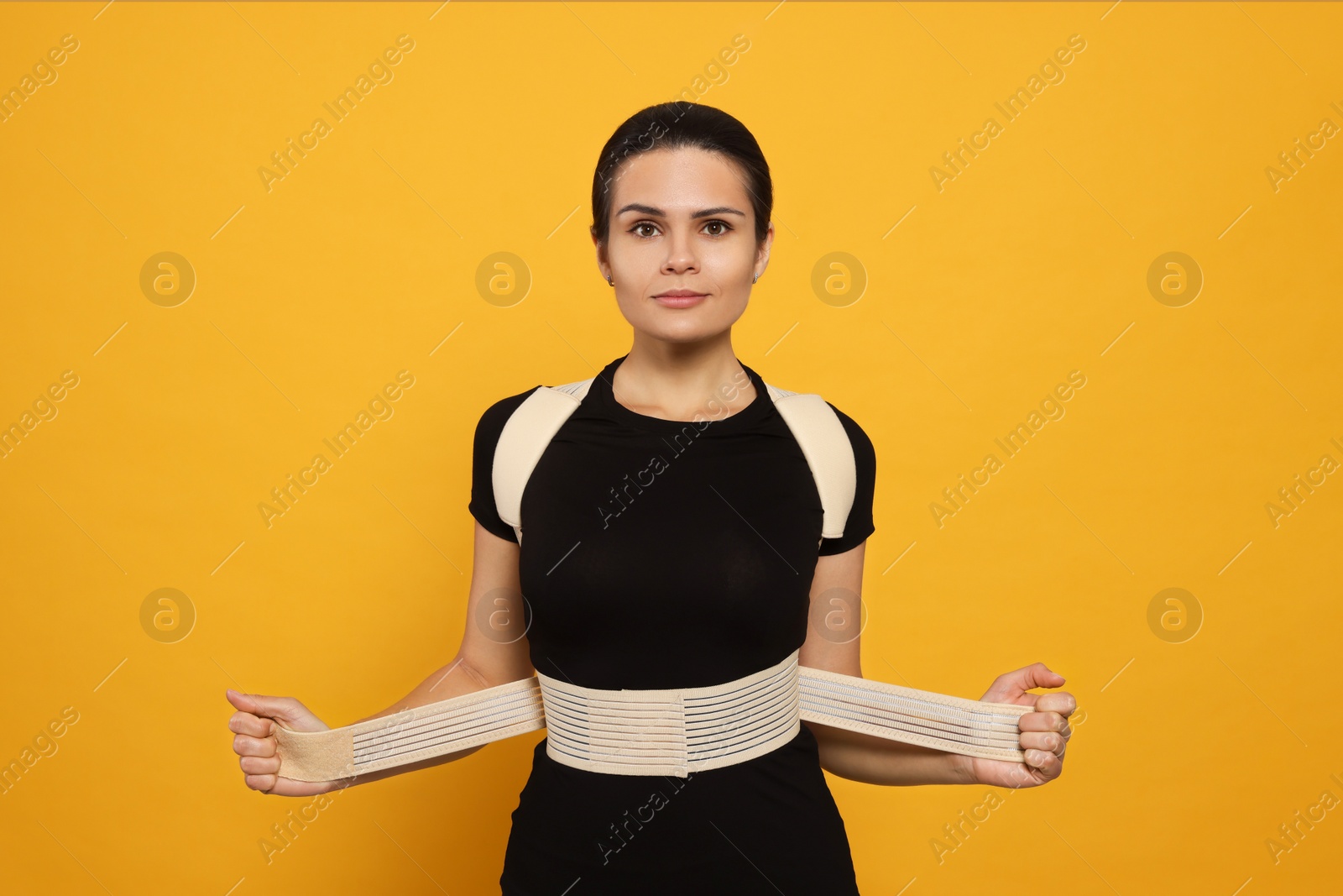 Photo of Beautiful woman with orthopedic corset on orange background