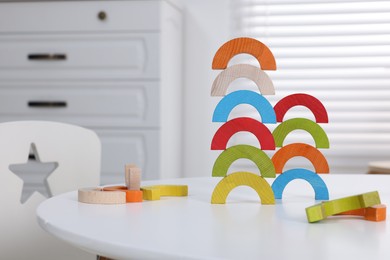 Photo of Colorful wooden pieces of educational toy on white table in room. Motor skills development