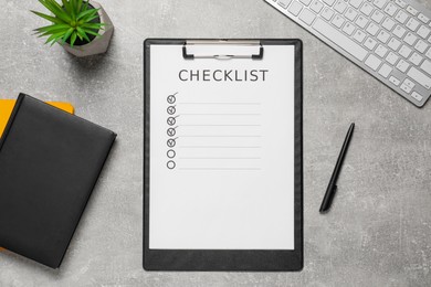 Clipboard with inscription Checklist, plant and computer keyboard on grey table, flat lay