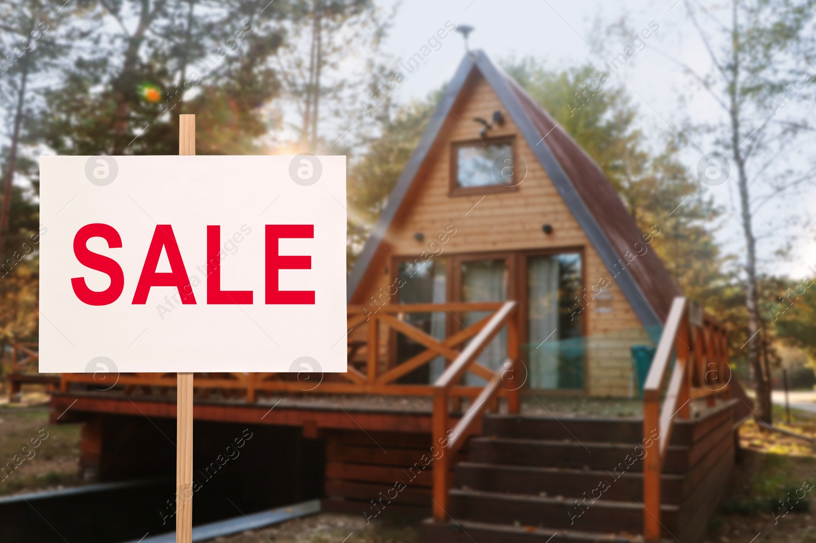 Image of Sale sign near beautiful house outdoors. White signboard with word