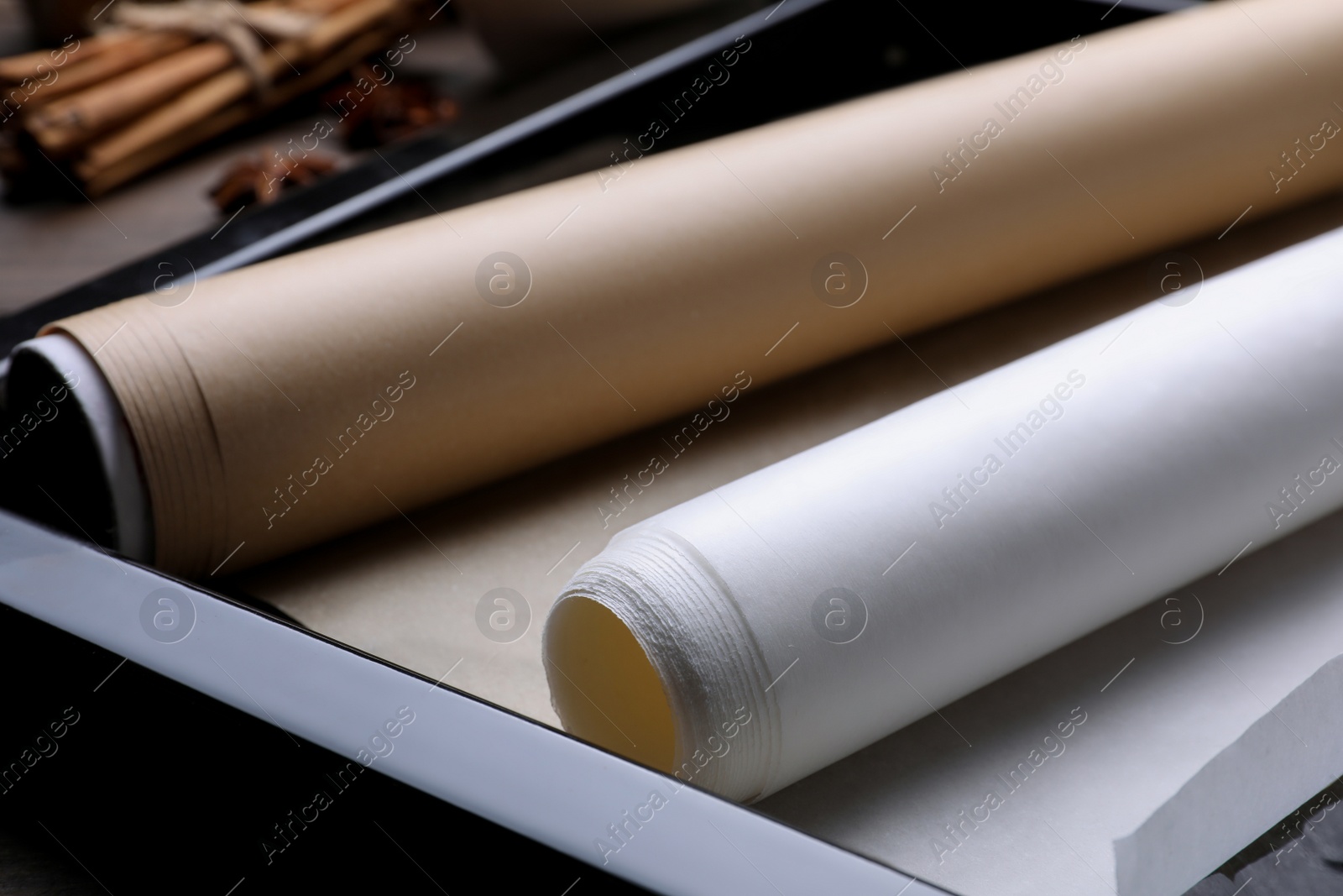 Photo of Rolls of parchment paper in baking pan on table, closeup