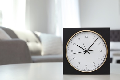 Analog alarm clock on table in living room. Time of day