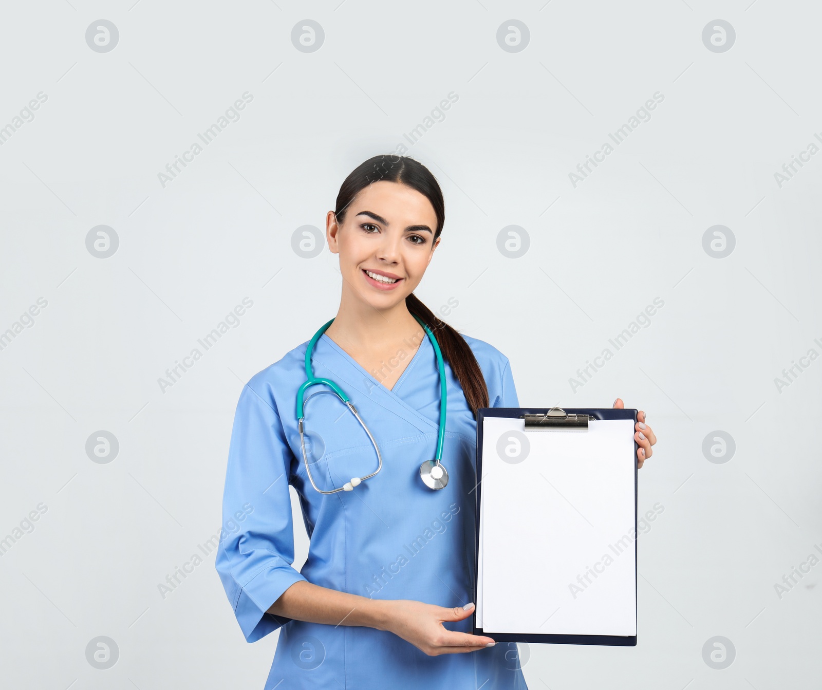 Photo of Portrait of medical assistant with stethoscope and clipboard on light background. Space for text