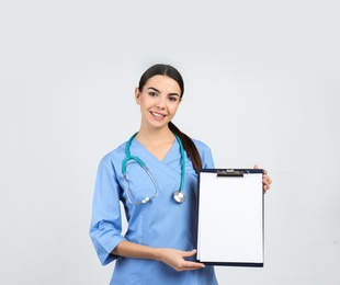 Photo of Portrait of medical assistant with stethoscope and clipboard on light background. Space for text