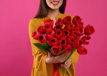 Photo of Happy woman with red tulip bouquet on pink background, closeup. 8th of March celebration