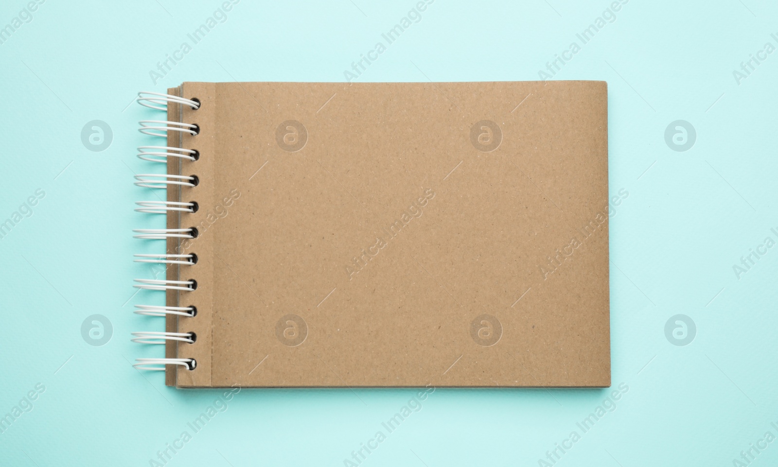 Photo of Notebook with brown paper pages on light blue background, top view