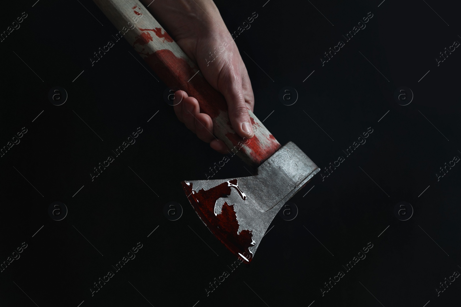 Photo of Man holding bloody axe on black background, closeup